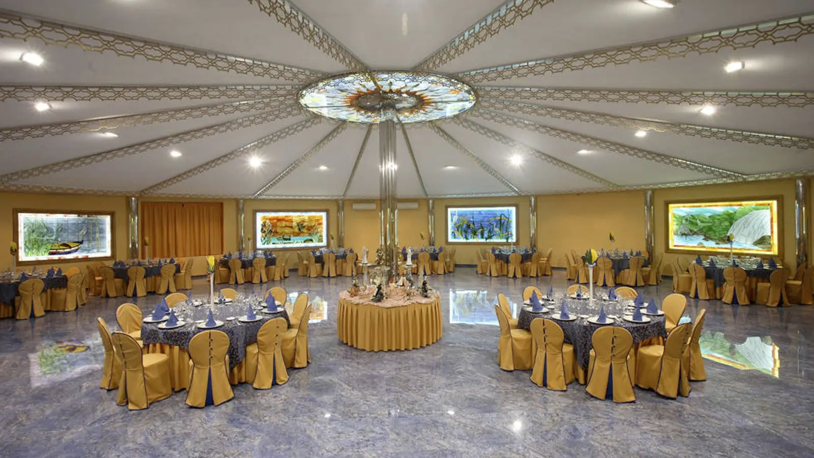 El Salón Plaza: una sala redonda con techo en forma de carpa, una claraboya de vidrieras y mesas vestidas de azul y oro