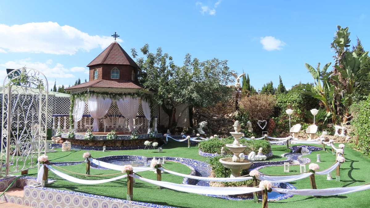 El templete de la ceremonia, un pabellón octogonal de ladrillo con cortinas blancas, entre estanques de azulejo azul y blanco y una fuente, bajo un cielo azul